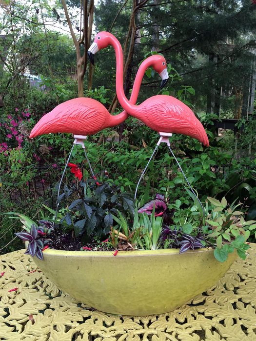 A pair of pink plastic flamingos in a planter